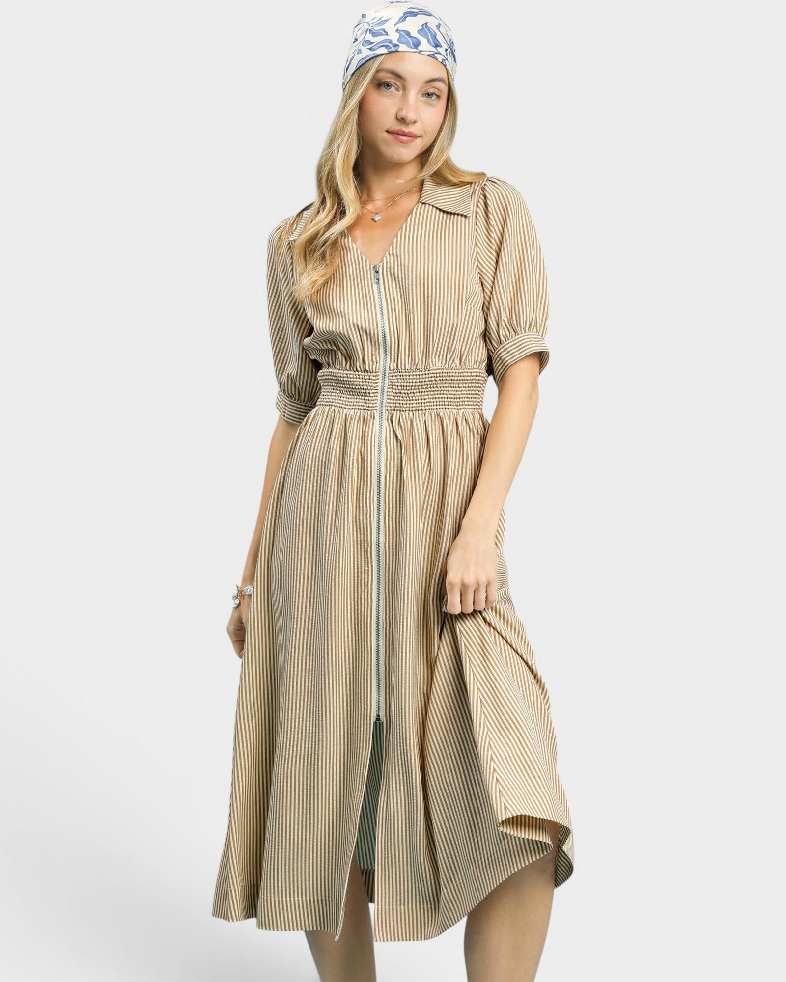 Woman wearing a beige striped dress with a belt on a white background