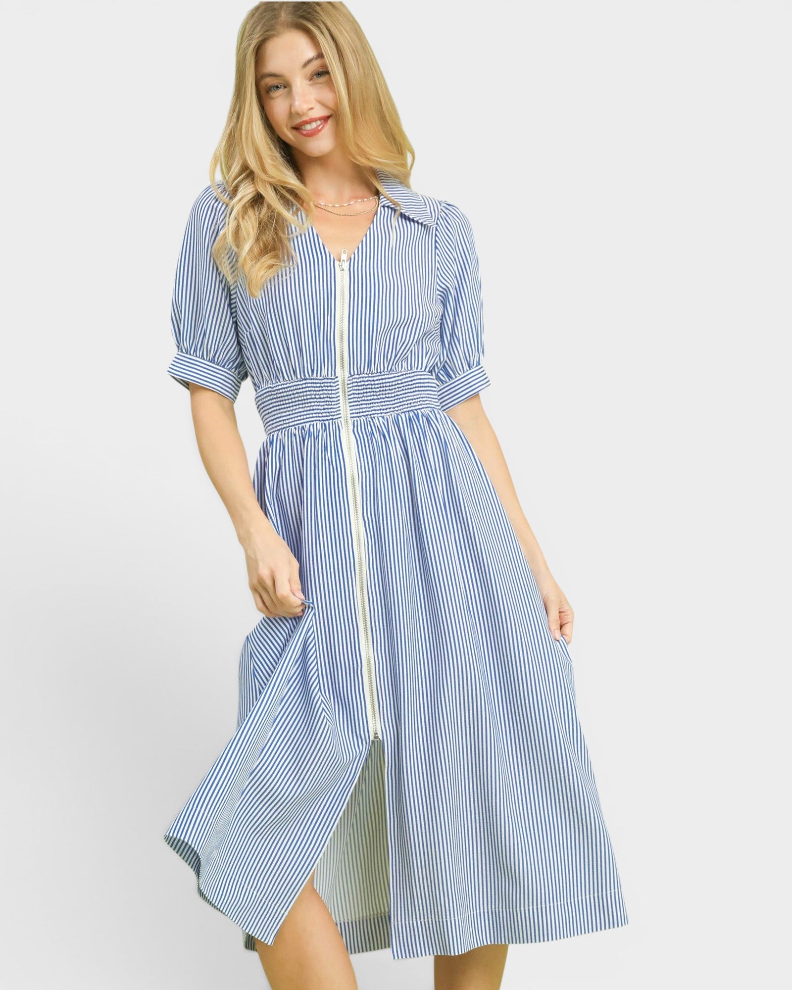 Woman wearing a blue and white striped dress on a light gray background