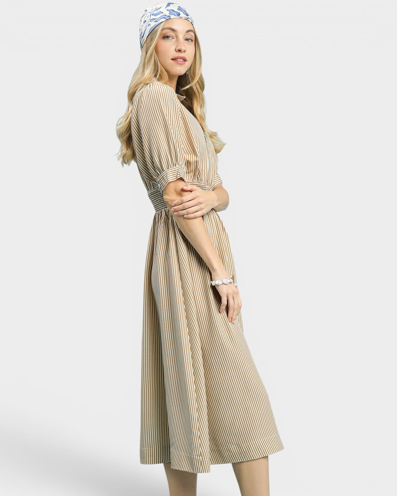 Woman wearing a long, striped dress with a plain background