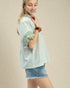 Woman wearing a light green striped shirt and denim shorts on a beige background