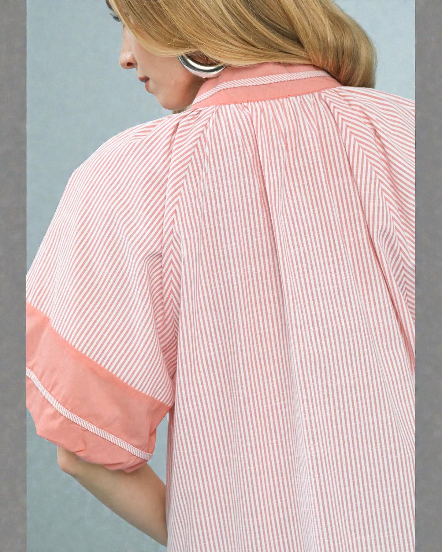 Woman wearing a pink and white striped shirt with a plain background