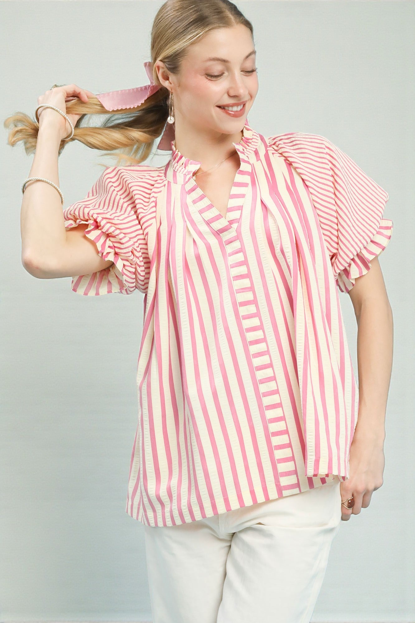 Woman wearing a pink and white striped blouse against a plain background