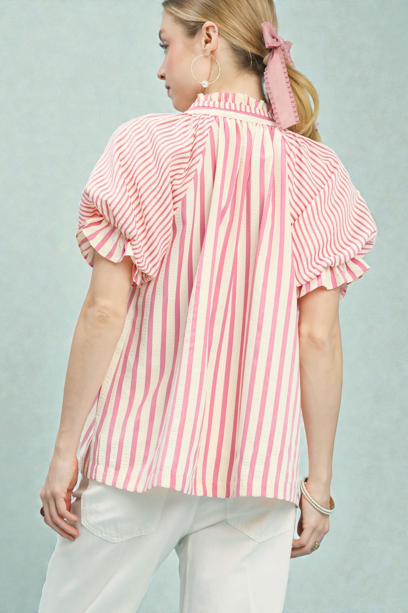 Woman wearing a pink and white striped blouse against a light gray background