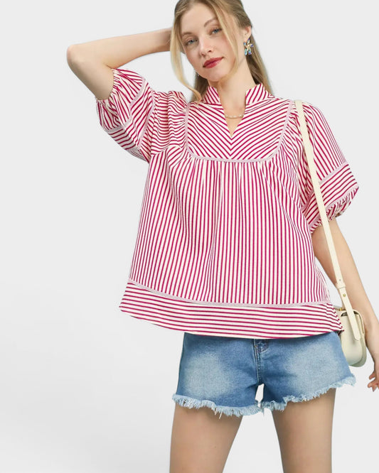 Woman wearing a red and white striped blouse and denim shorts on a light gray background