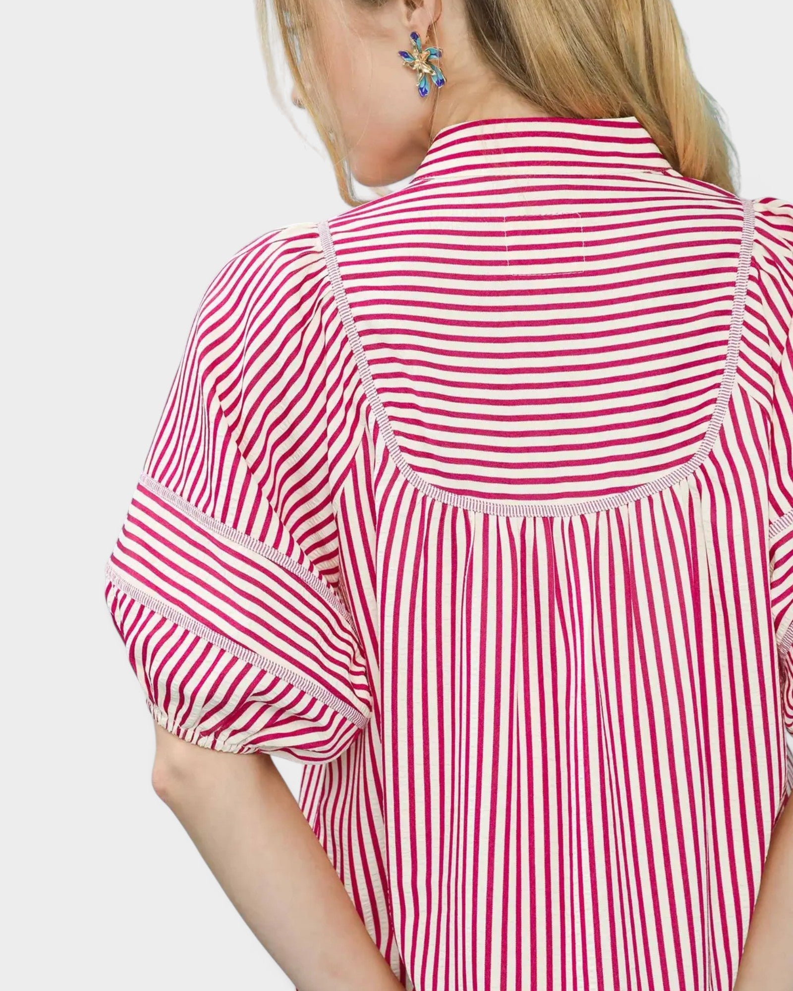 Red and white striped shirt worn by a person on a plain background
