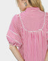 Red and white striped shirt worn by a person on a plain background