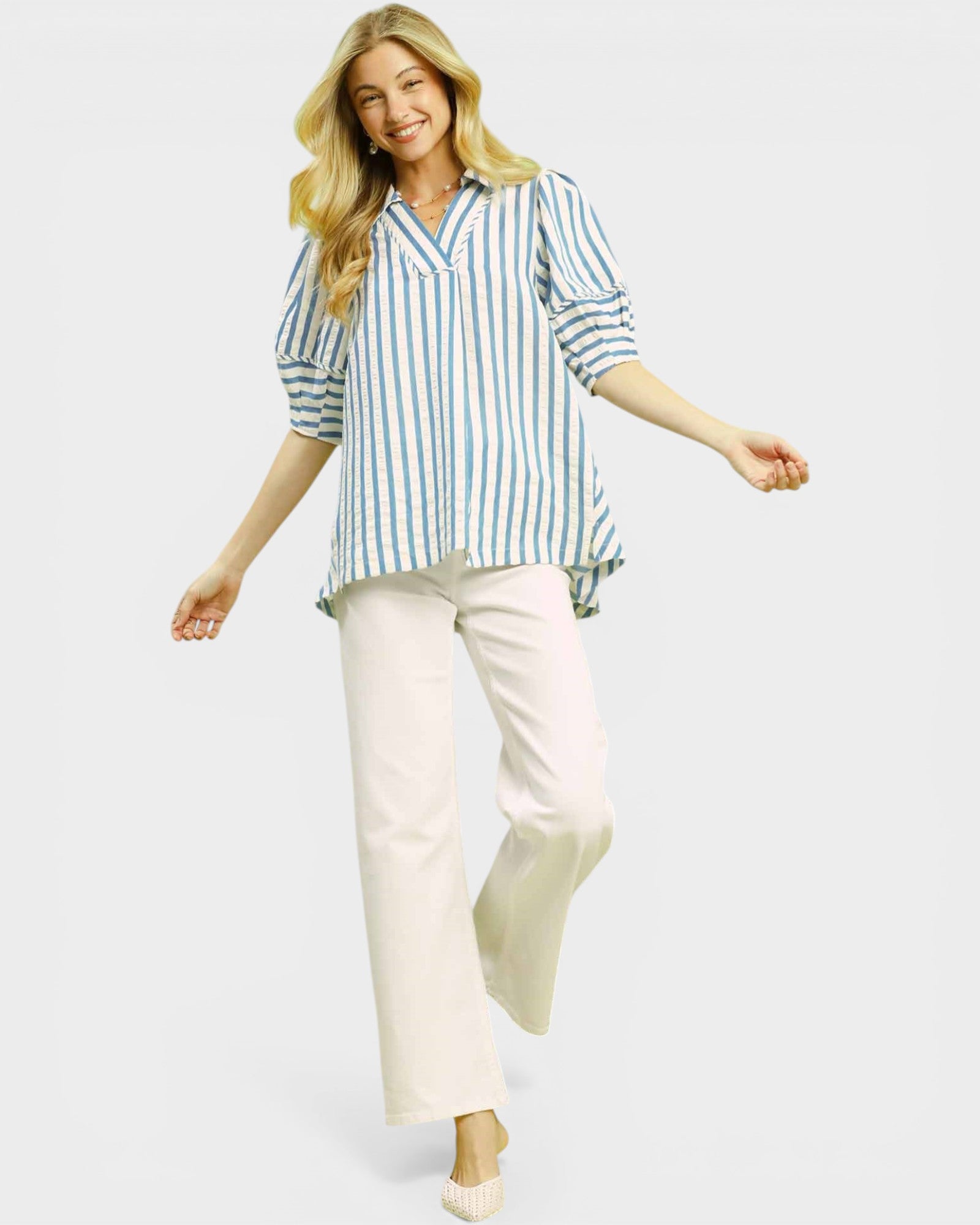 Woman wearing a striped shirt and white pants on a light gray background