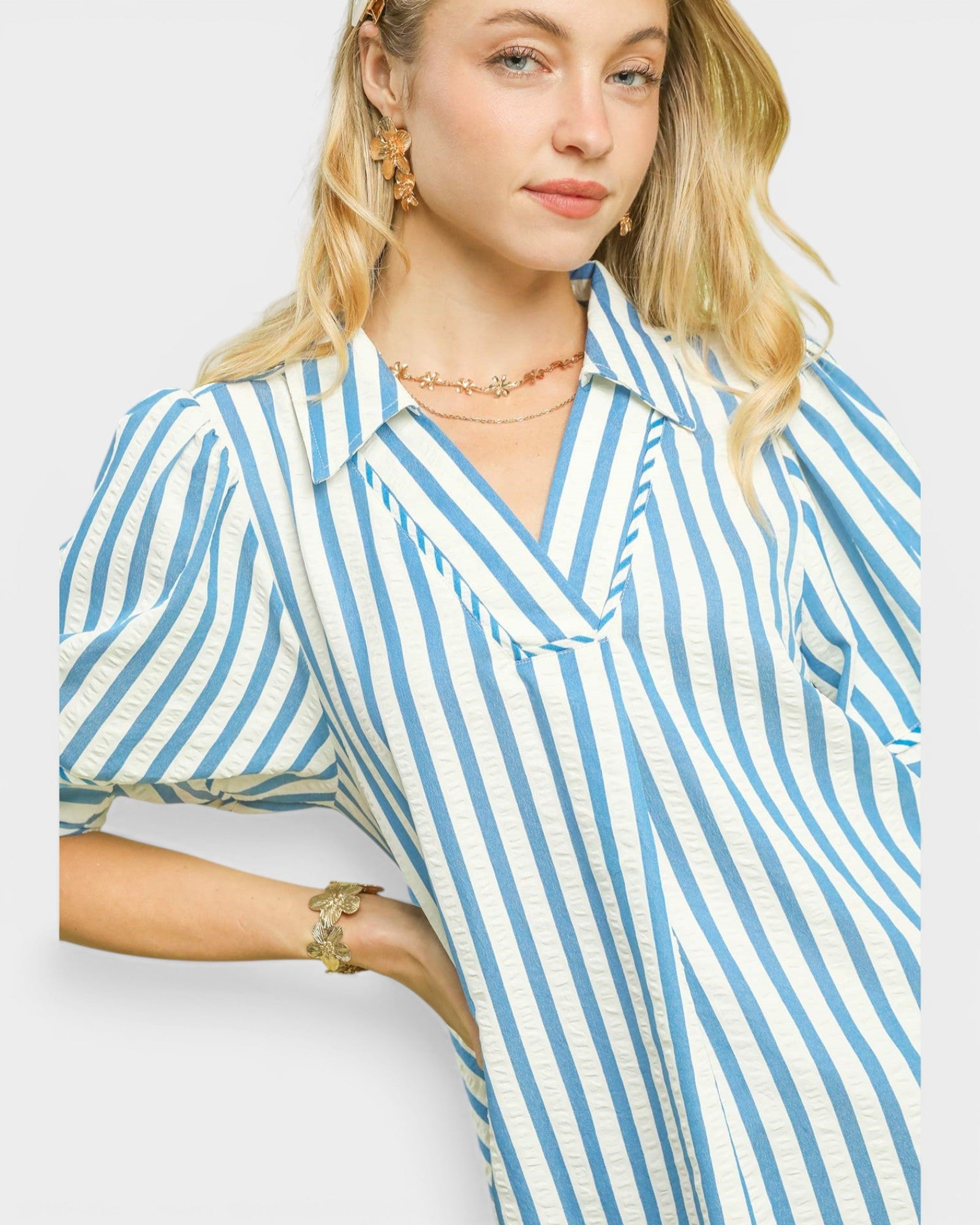 Woman wearing a blue and white striped shirt against a plain background