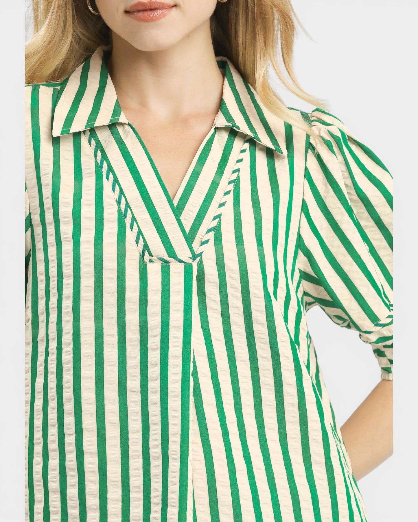 Green and white striped shirt worn by a person on a light gray background