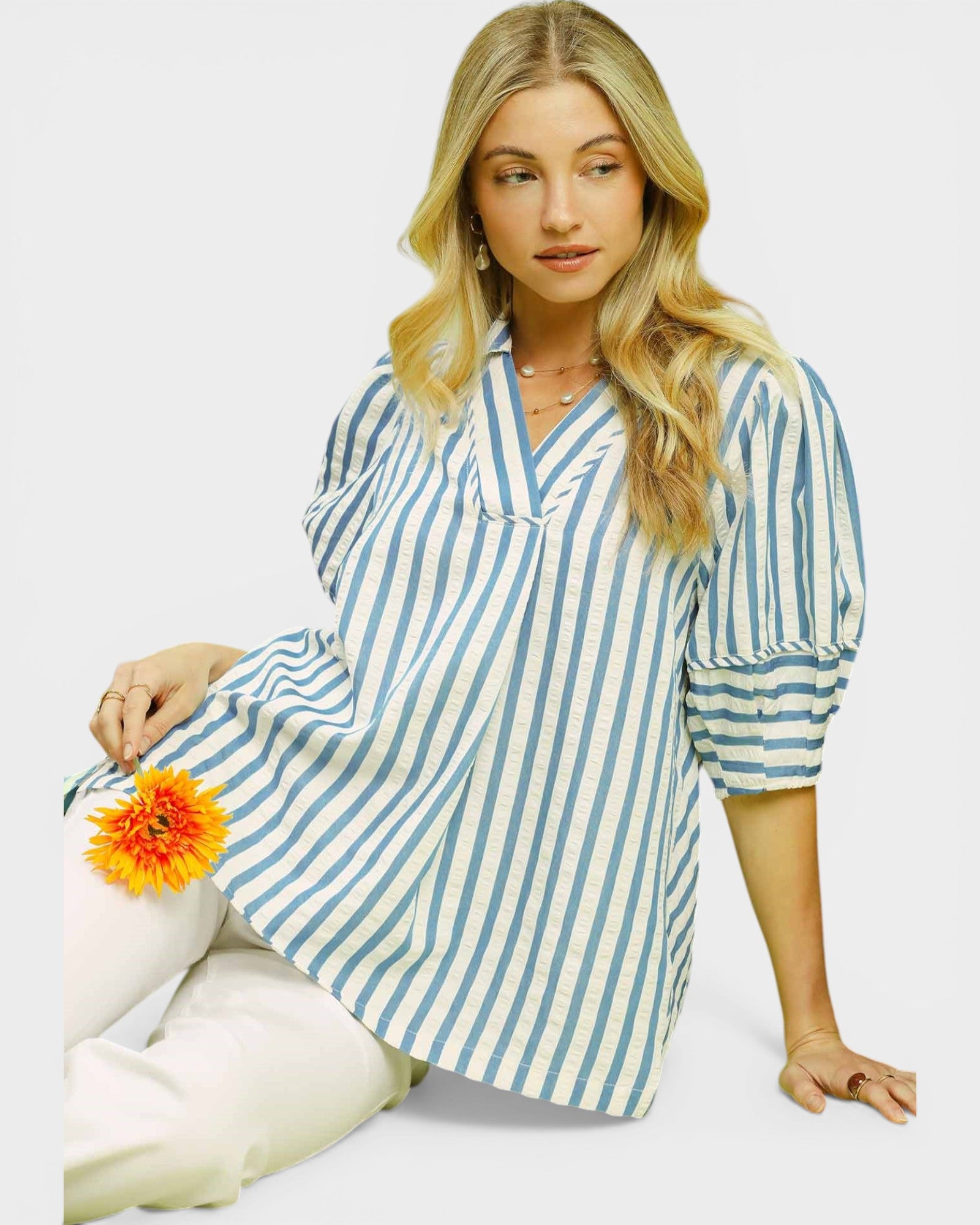 Woman wearing a blue and white striped dress with a yellow flower on a white background