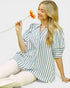 Woman wearing a blue and white striped shirt holding a flower against a white background