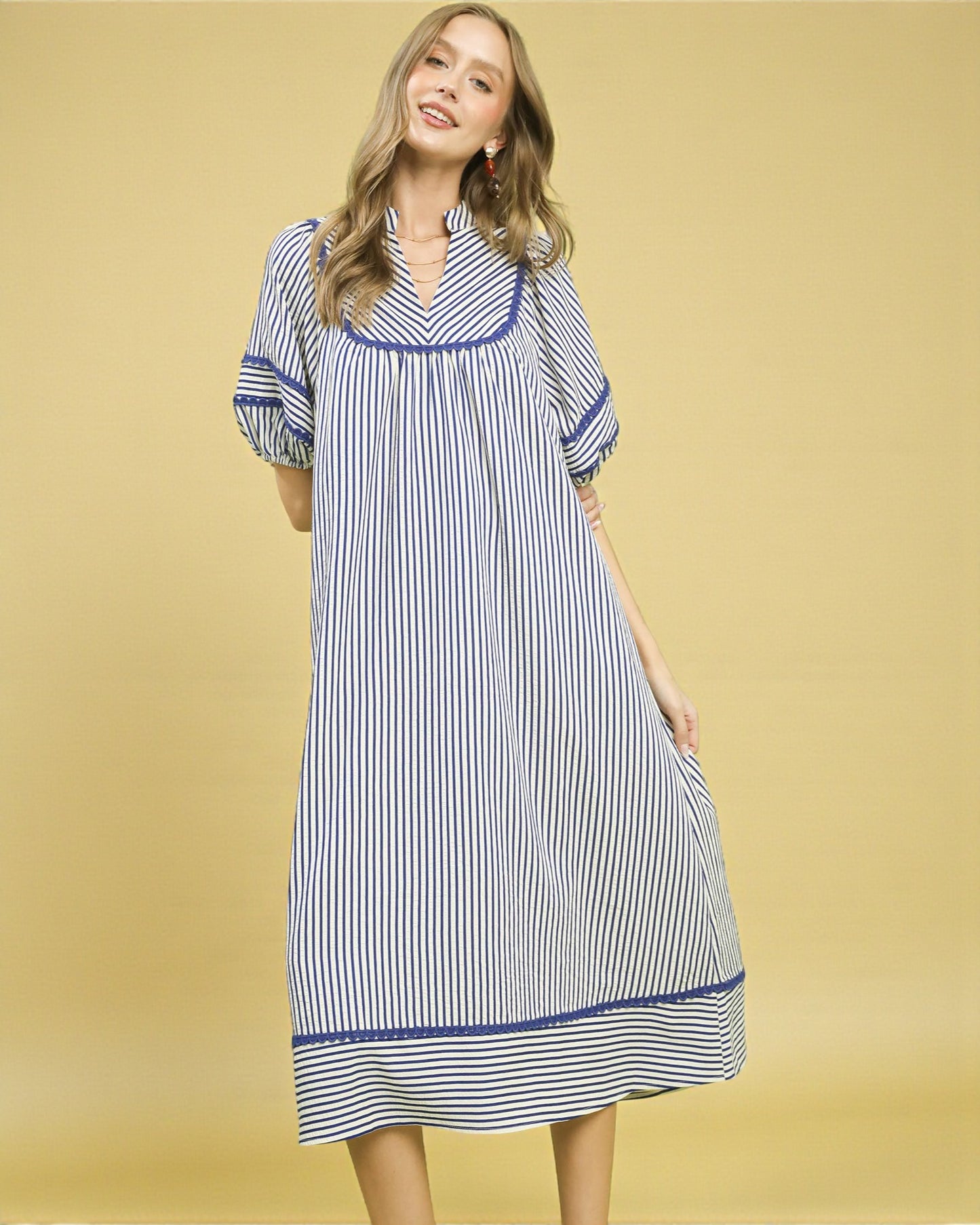 Woman wearing a blue and white striped dress on a yellow background