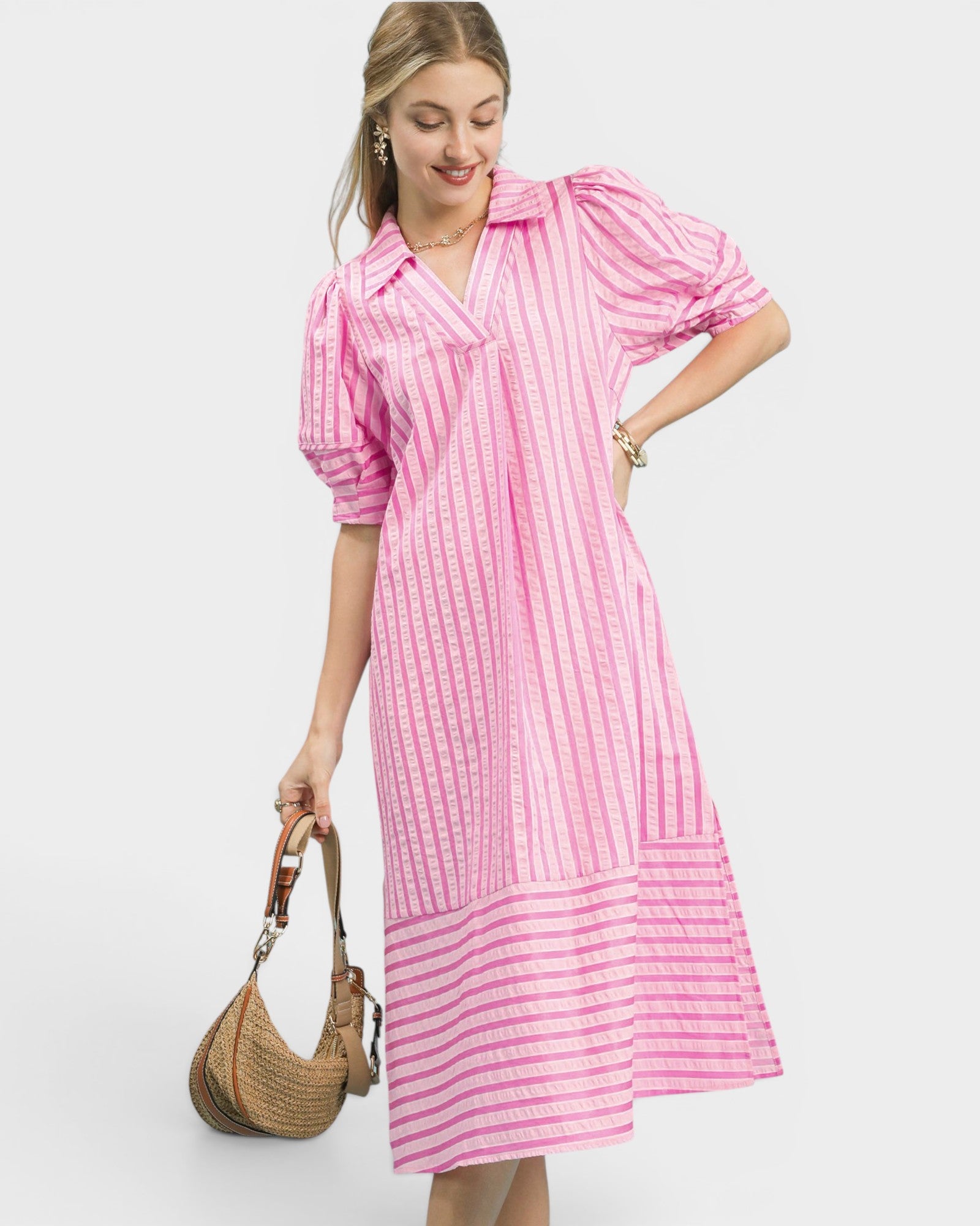 Woman wearing a pink and white striped dress holding a straw bag on a white background