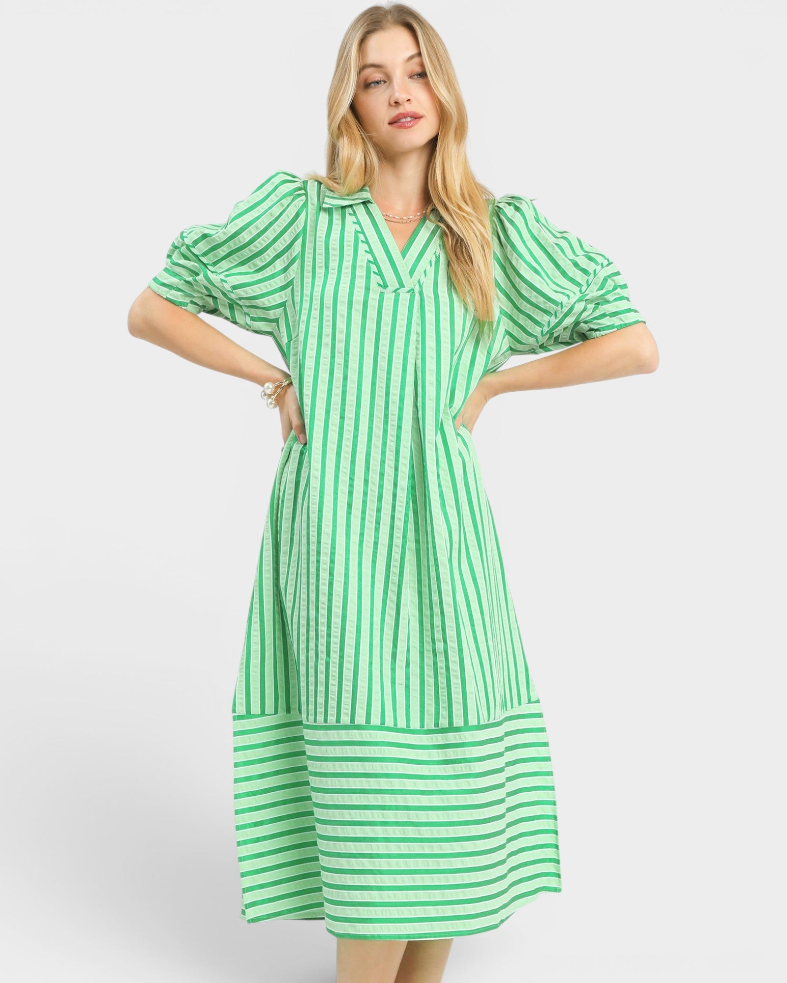 Woman wearing a green and white striped dress on a white background