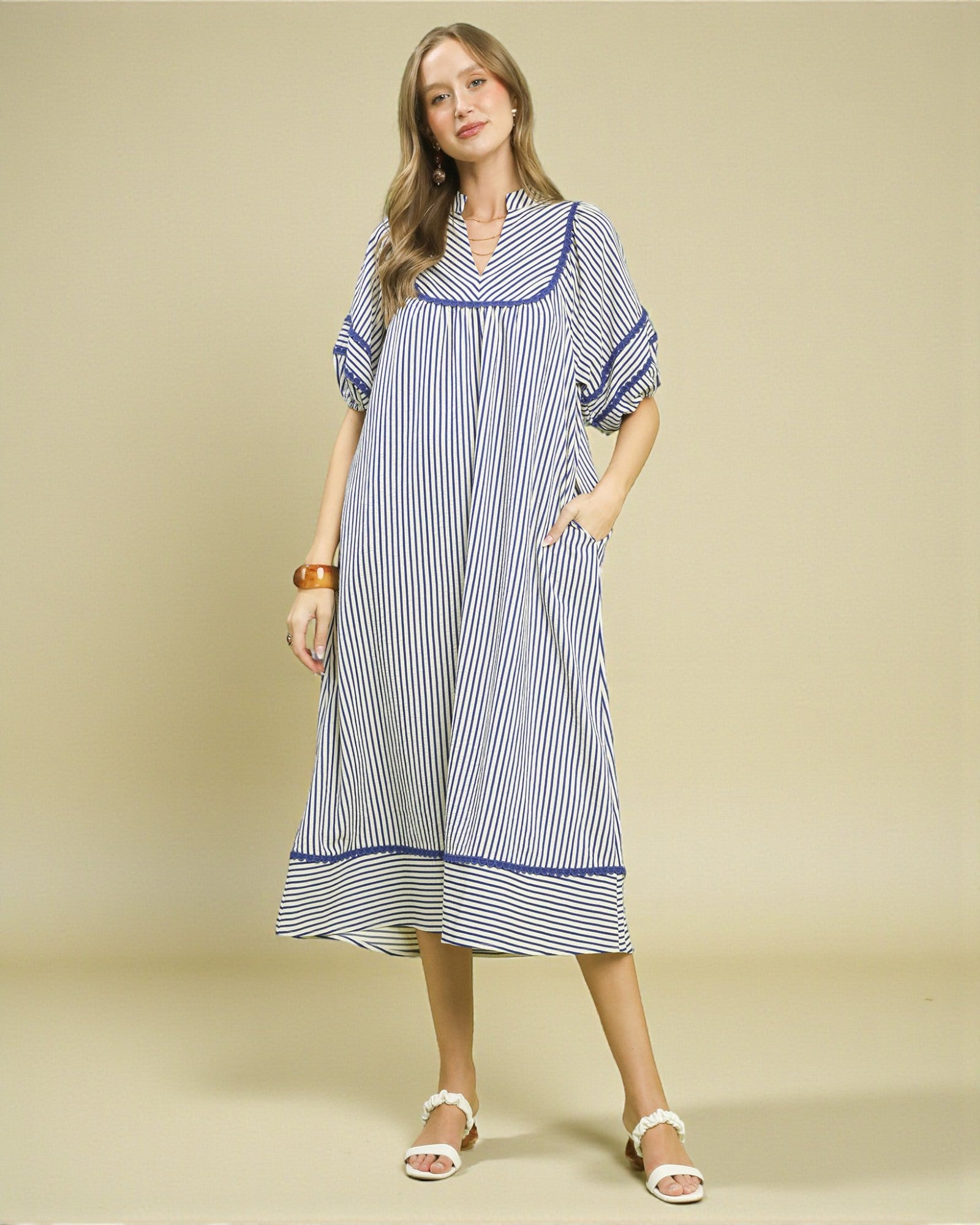 Woman wearing a blue and white striped dress on a beige background