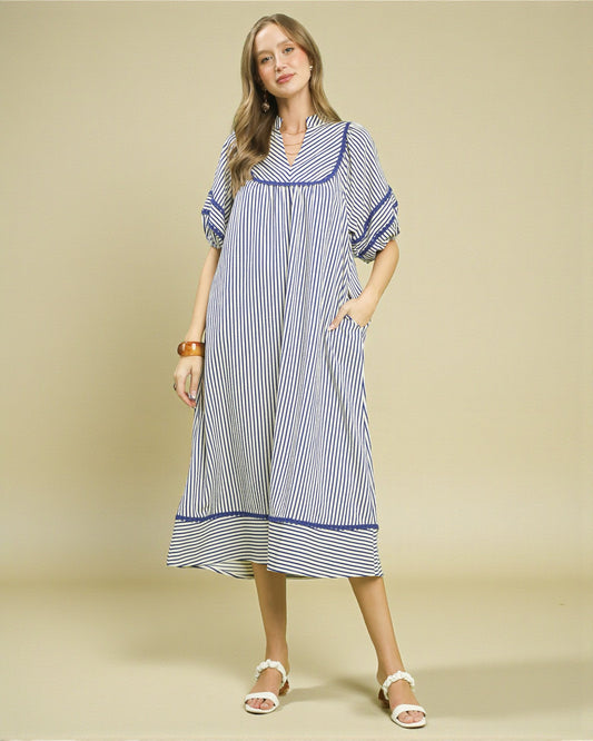 Woman wearing a blue and white striped dress on a beige background