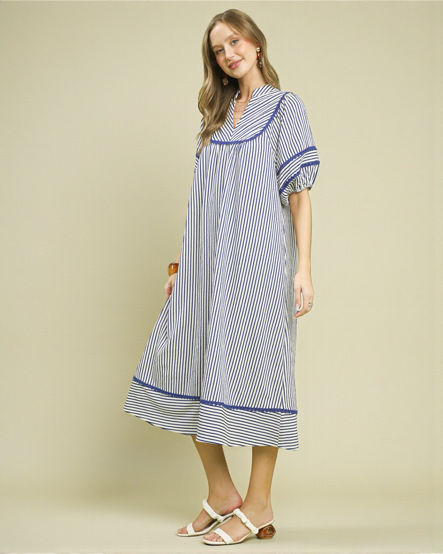 Woman wearing a blue and white striped dress on a beige background