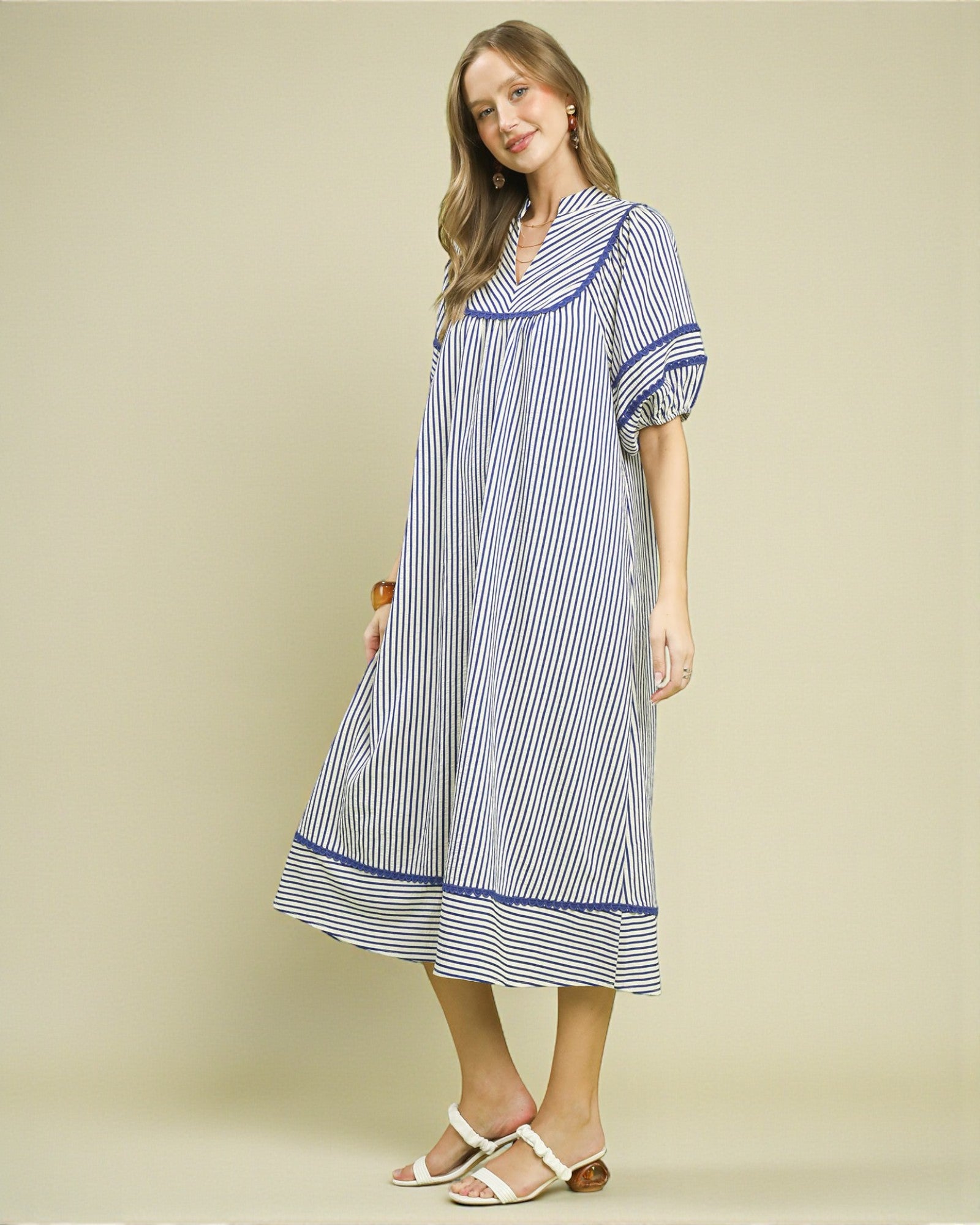 Woman wearing a blue and white striped dress on a beige background