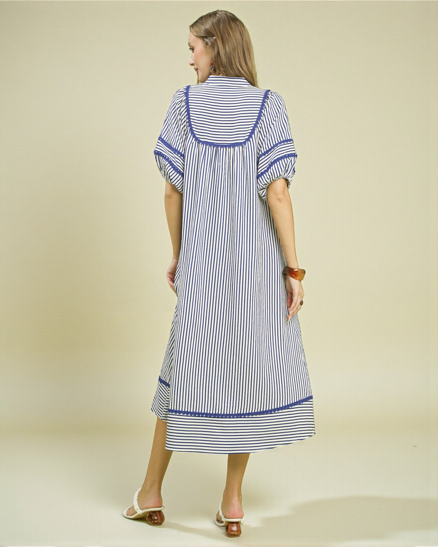 Woman wearing a blue and white striped dress on a beige background