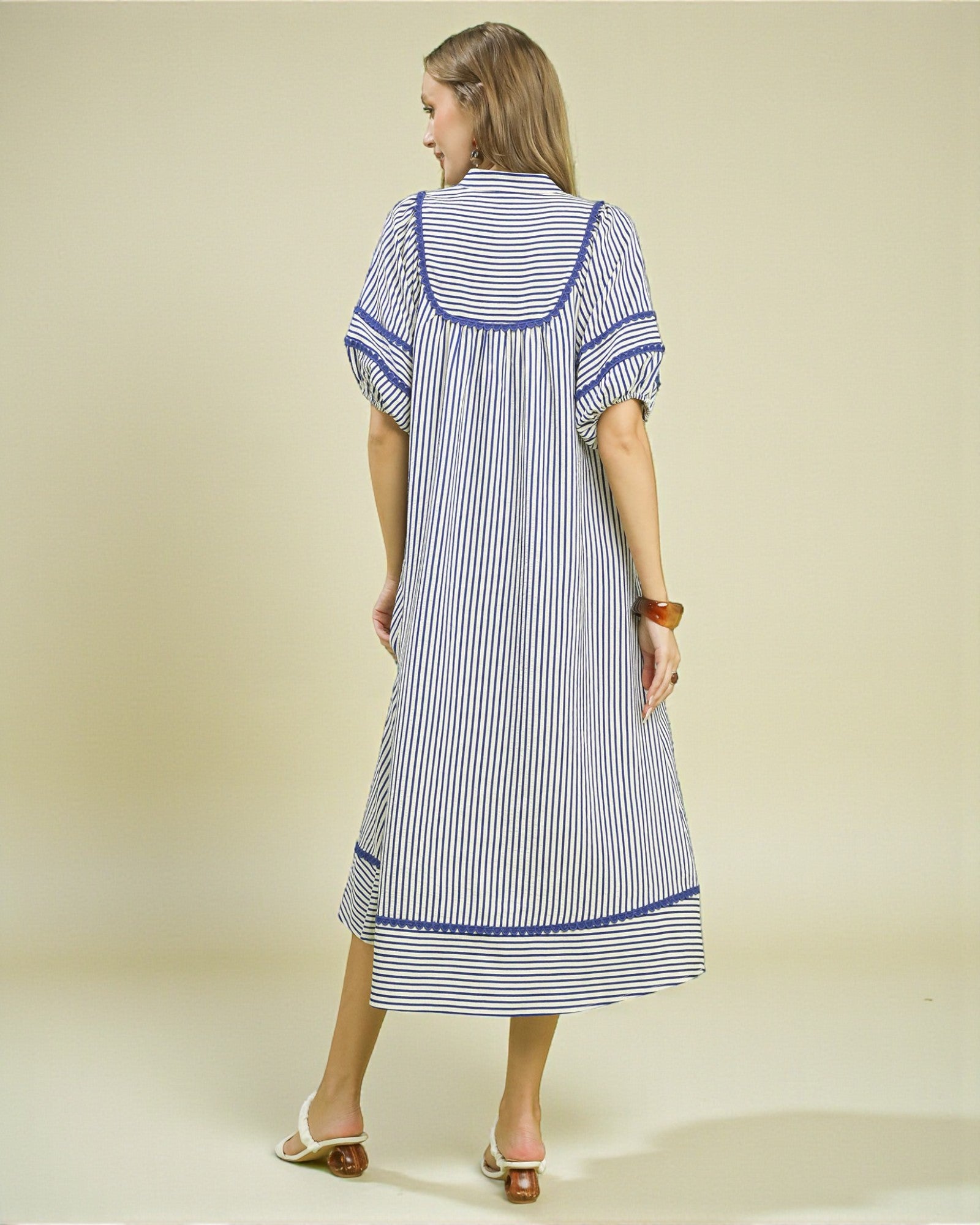 Woman wearing a blue and white striped dress on a beige background