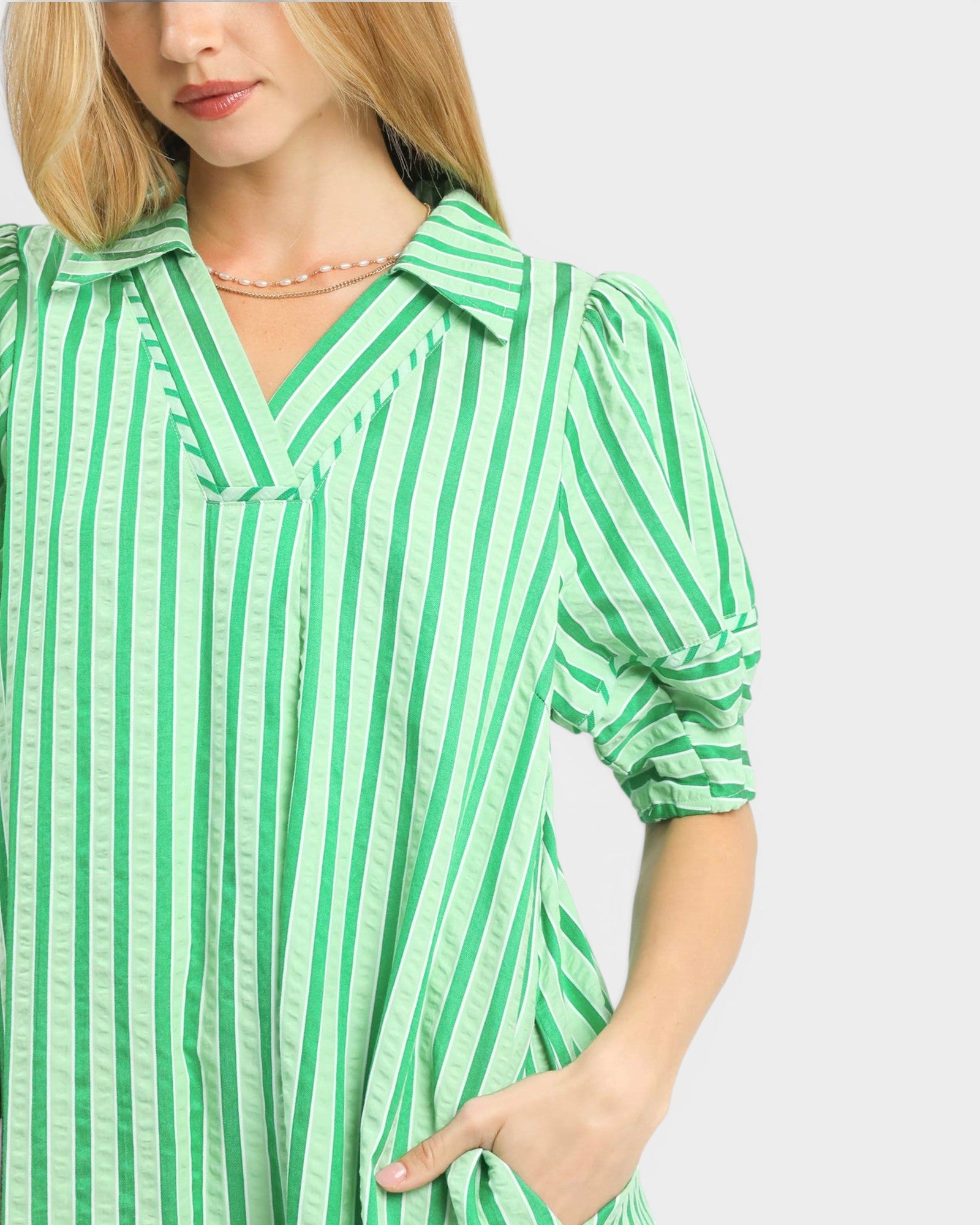 Woman wearing a green and white striped shirt on a plain background
