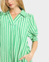 Woman wearing a green and white striped shirt on a plain background