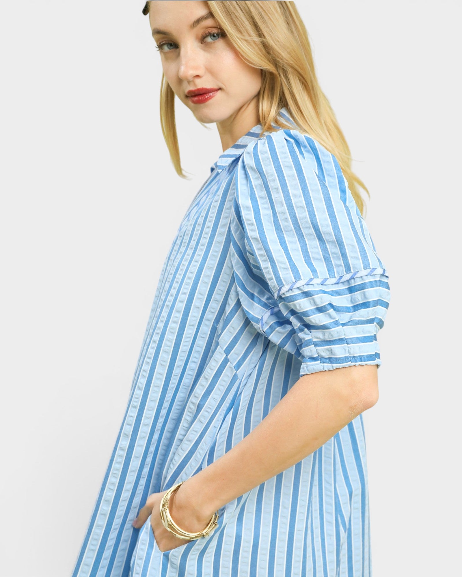Woman wearing a blue and white striped dress on a plain background