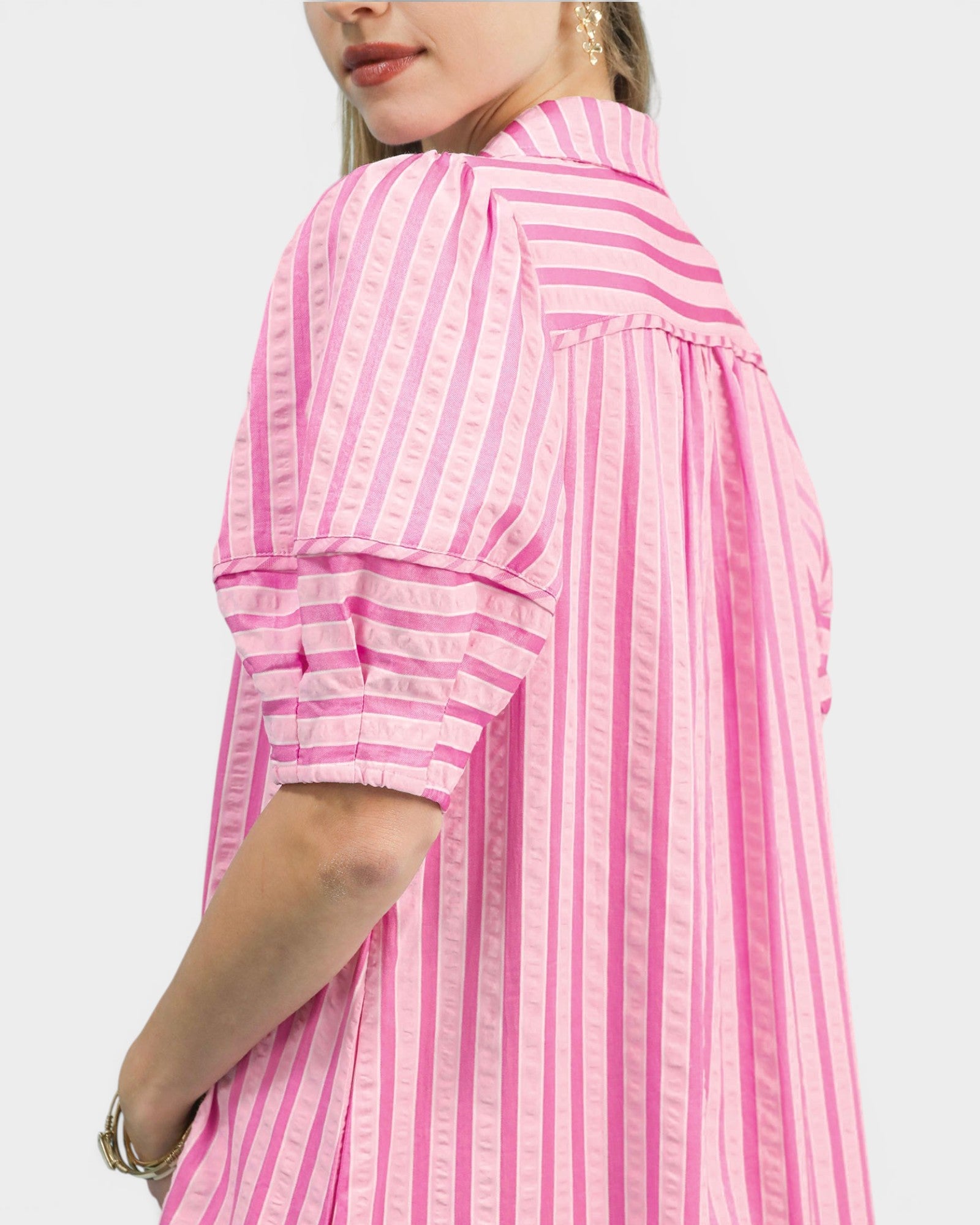 Pink and white striped dress worn by a person on a light gray background