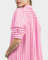Pink and white striped dress worn by a person on a light gray background