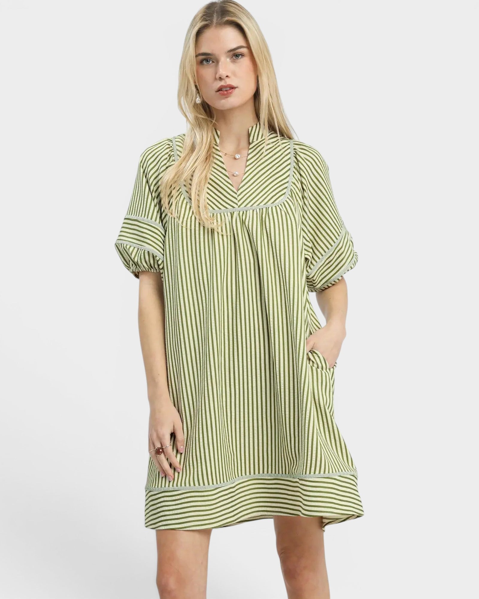 Woman wearing a green and white striped dress on a white background