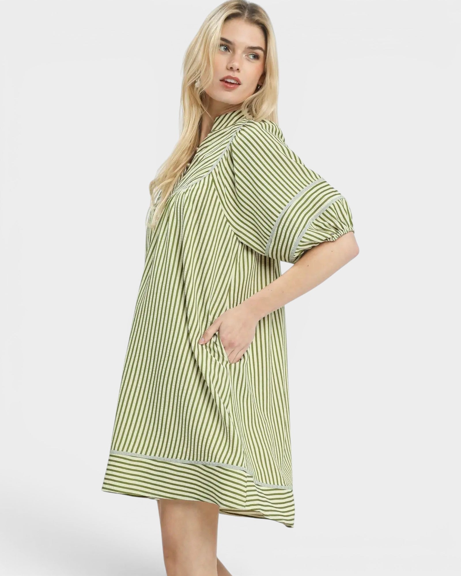 Woman wearing a green and white striped dress on a white background