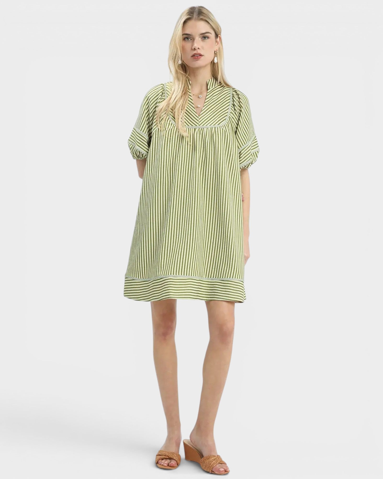 Woman wearing a green and white striped dress on a white background