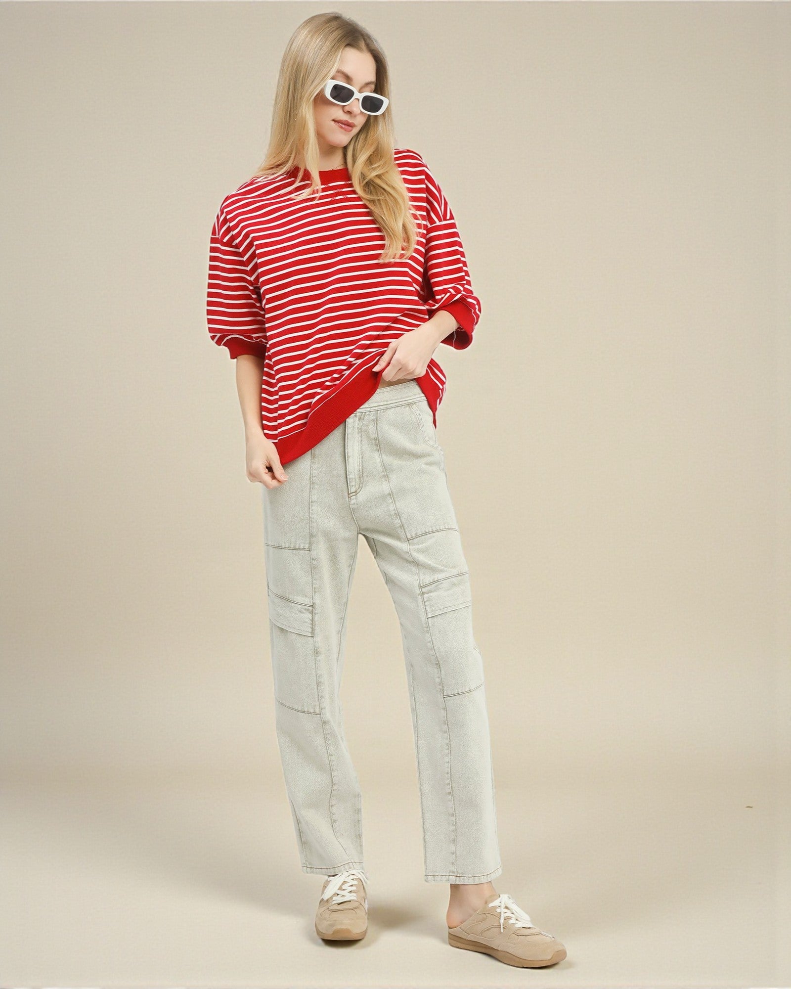 Person wearing a red and white striped sweater and light gray pants on a beige background