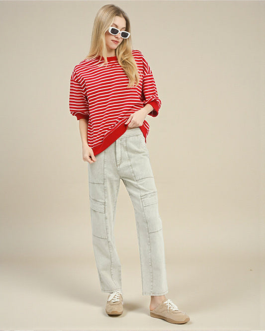 Person wearing a red and white striped sweater and light gray pants on a beige background