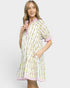 Woman wearing a patterned dress with pink trim on a white background