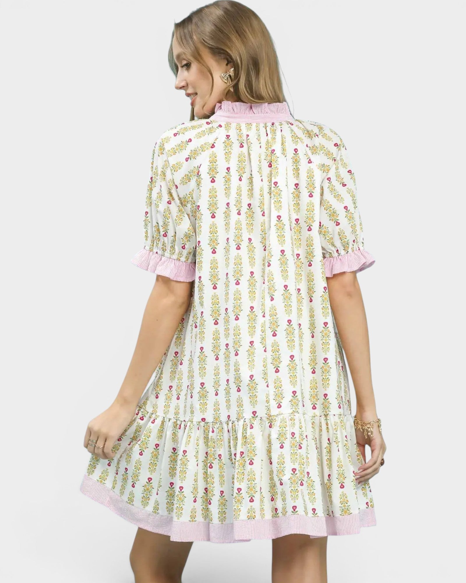 Woman wearing a floral dress with pink trim on a white background