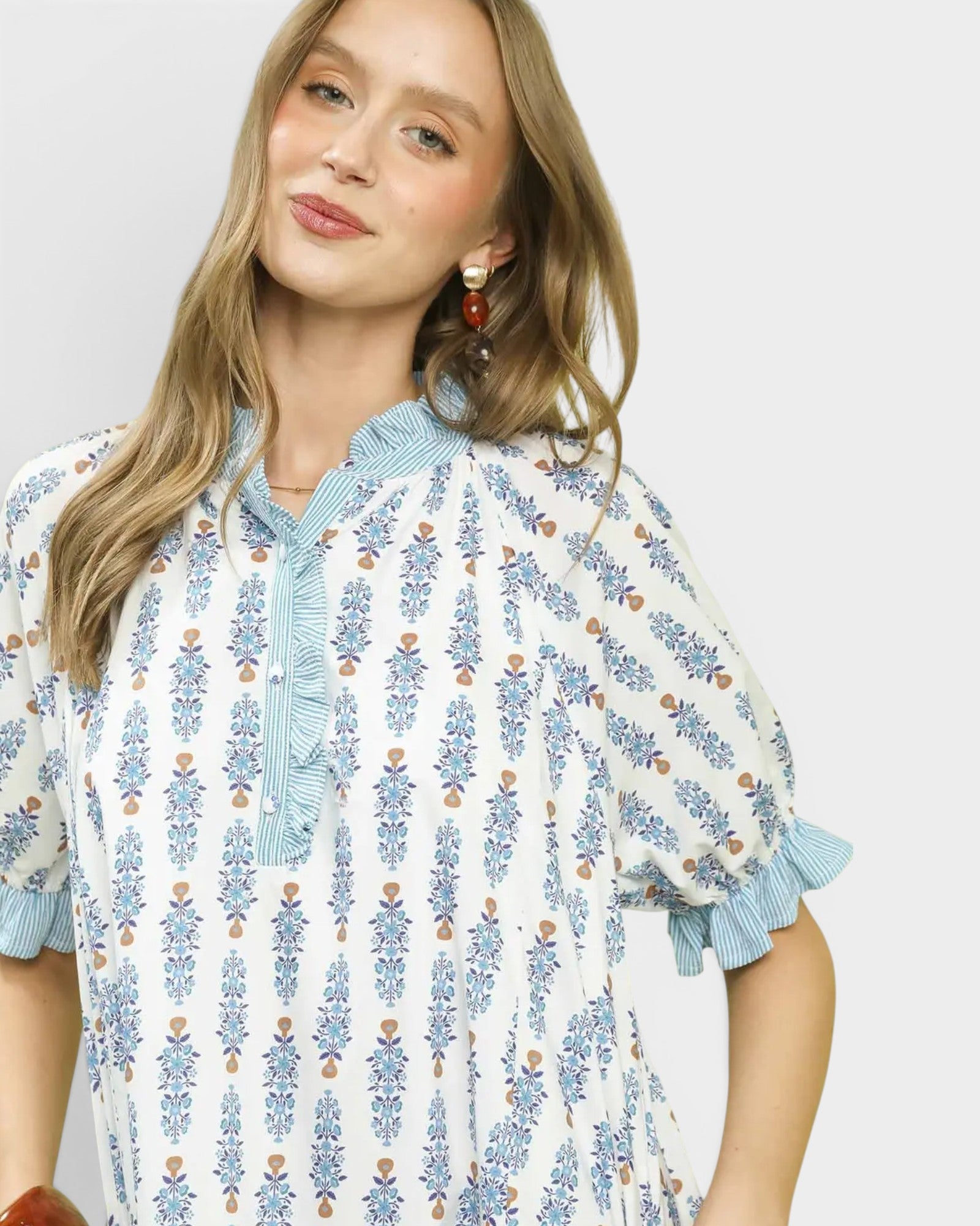 Woman wearing a floral dress with blue accents on a plain background