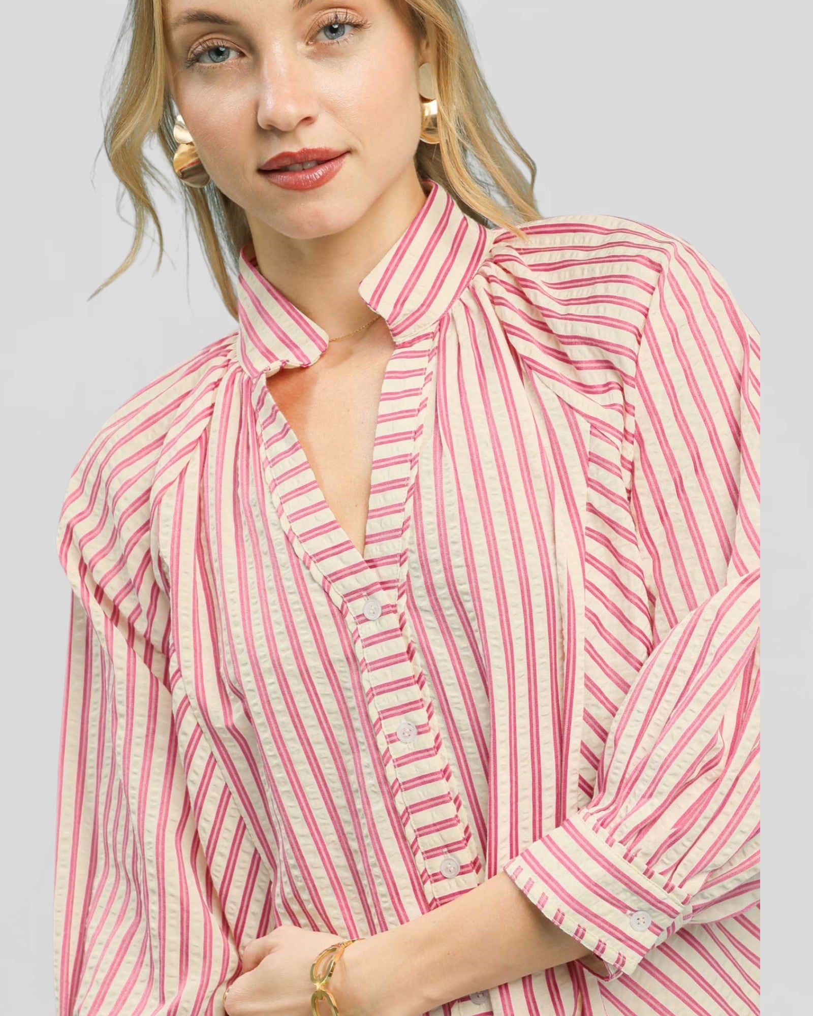 Woman wearing a pink and white striped blouse against a plain background