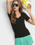 Woman wearing a black top and green skirt holding a volleyball against a light gray background