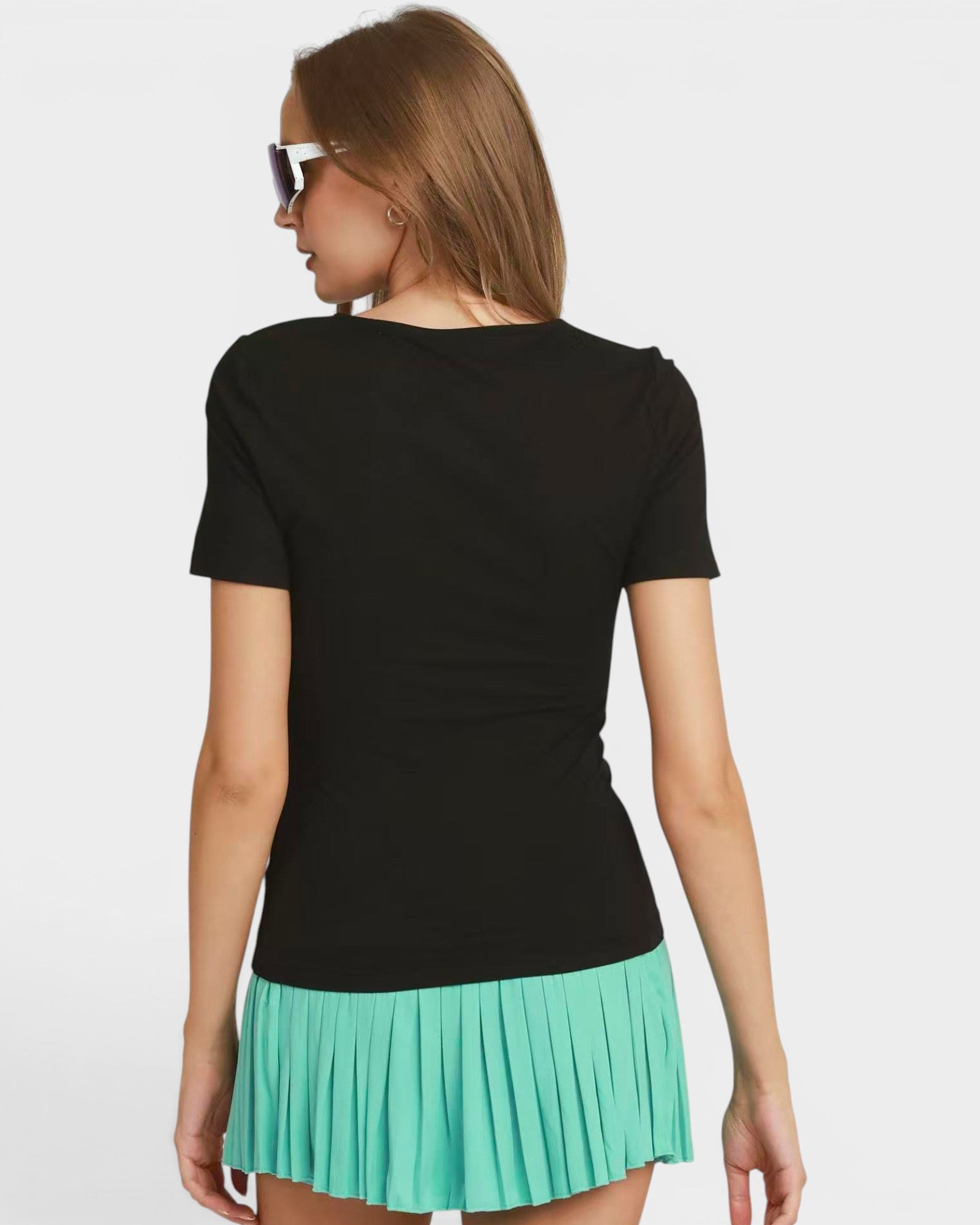 Woman wearing a black top and green pleated skirt on a white background