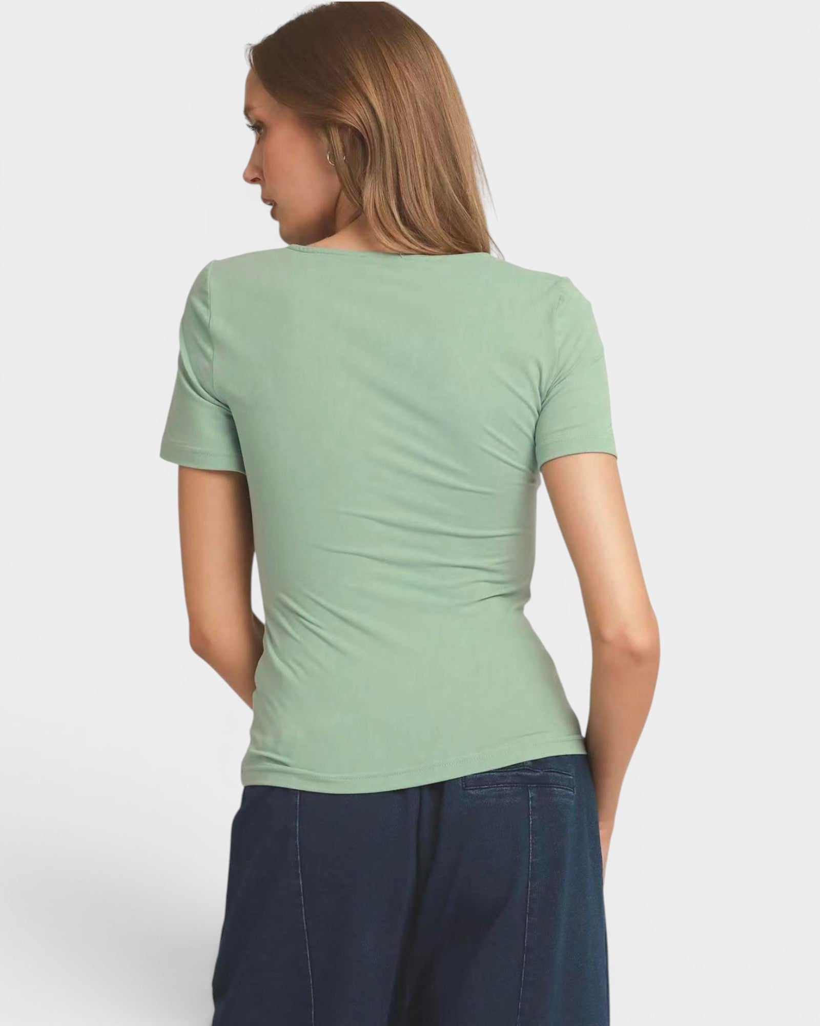 Woman wearing a green t-shirt against a plain background