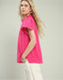 Woman wearing a bright pink pleated top against a light background