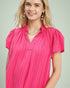 Woman wearing a pink pleated blouse against a light background