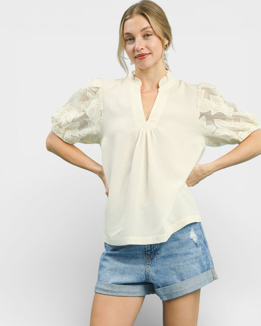 Woman wearing a light-colored blouse with puff sleeves and denim shorts on a white background