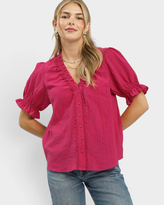 Woman wearing a pink blouse with ruffled sleeves on a white background