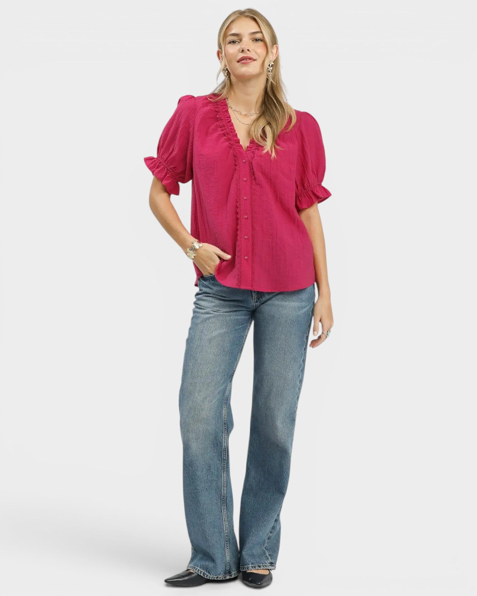 Woman wearing a pink blouse and blue jeans on a white background