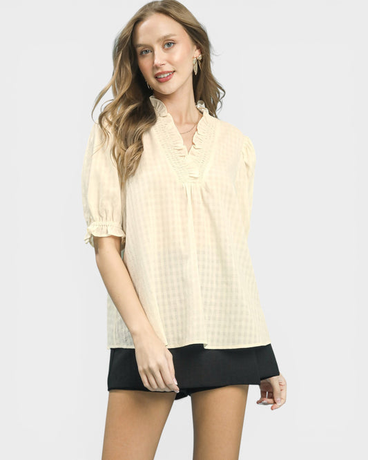 Woman wearing a beige blouse and black shorts on a white background