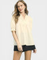 Woman wearing a beige blouse and black shorts on a white background