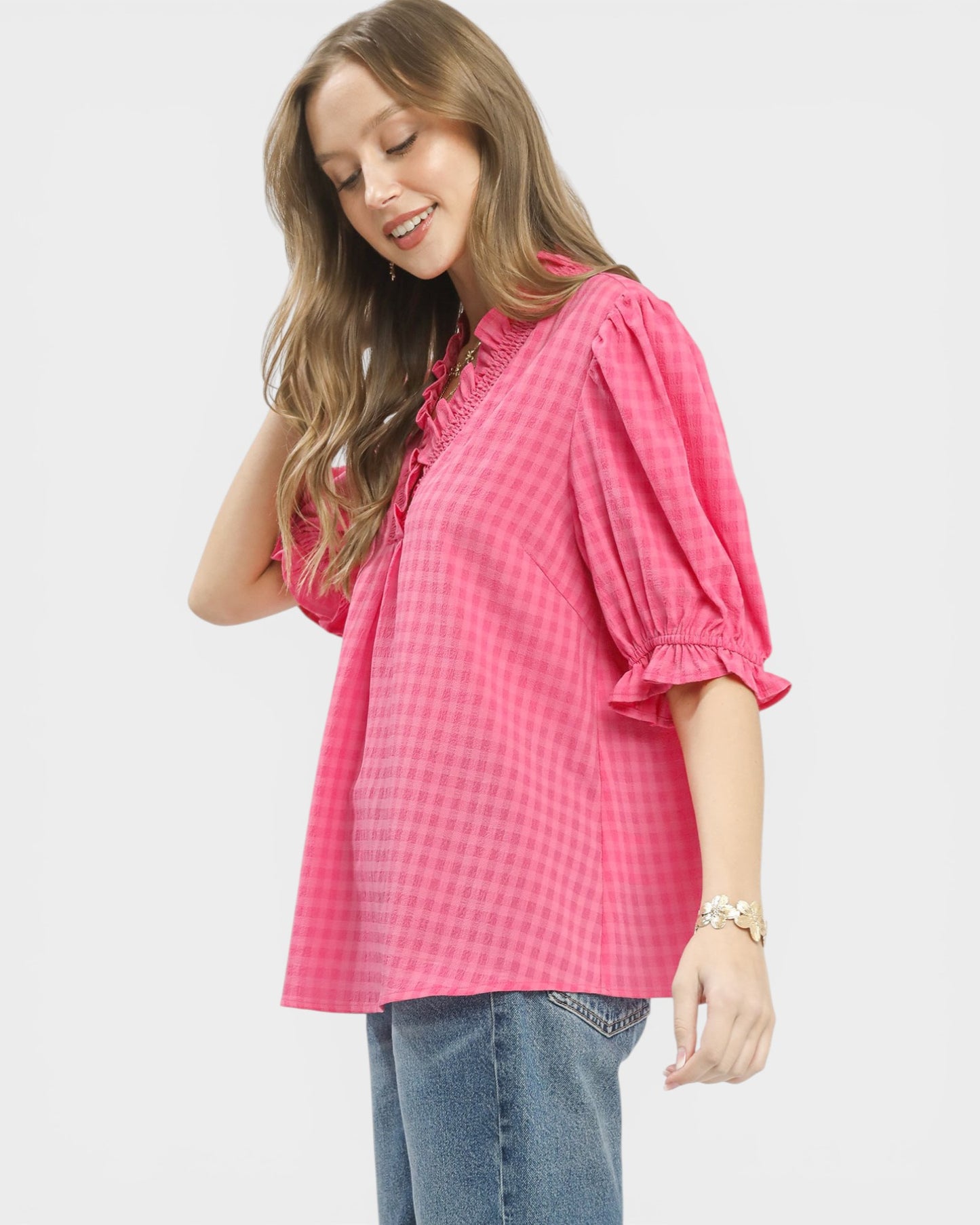 Woman wearing a pink checkered blouse with blue jeans on a white background