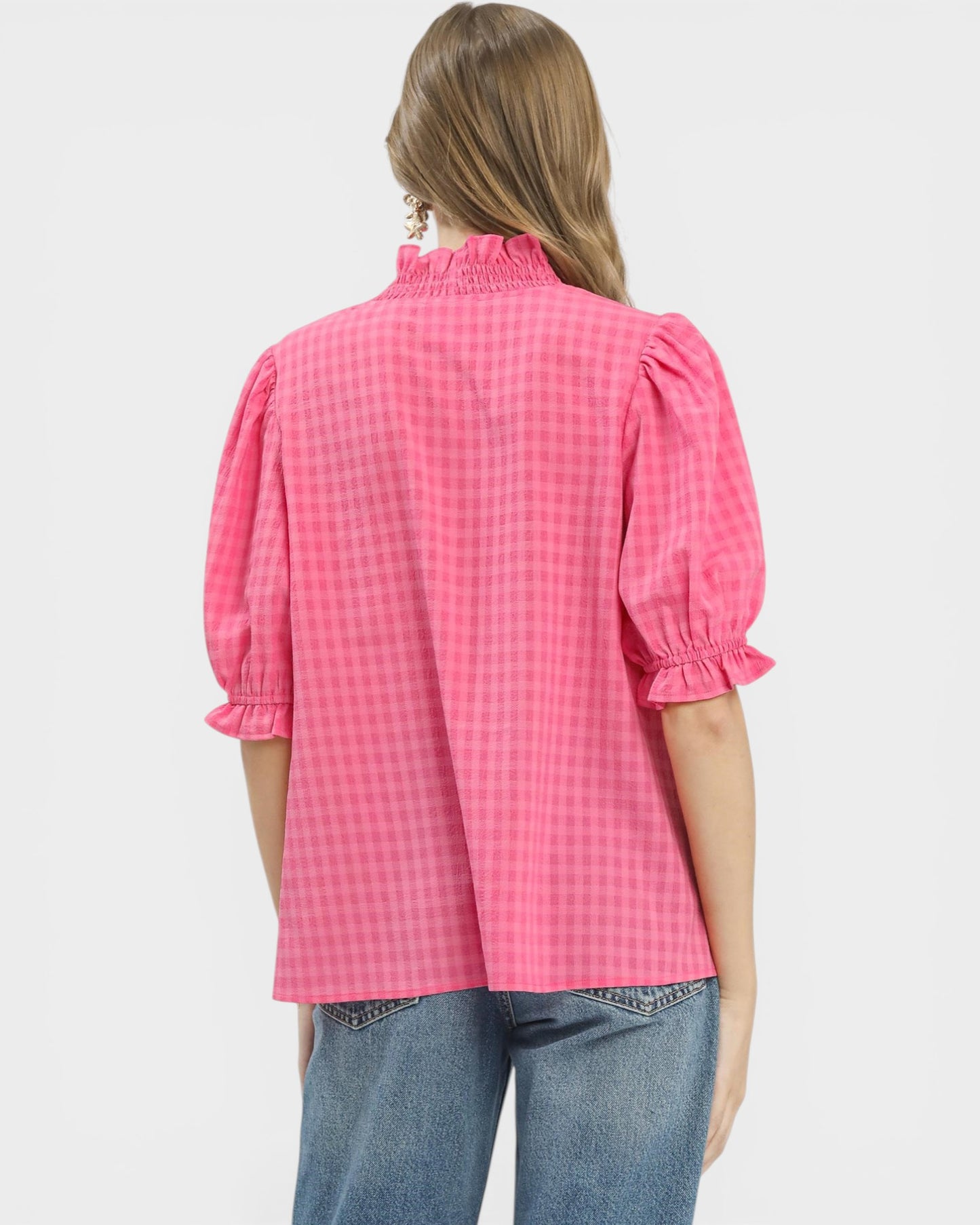 Person wearing a pink checkered blouse with puffed sleeves on a white background